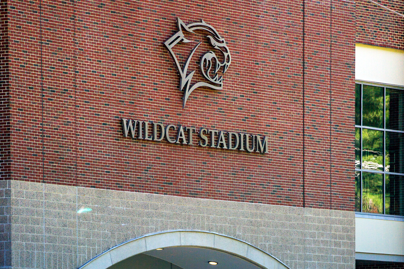 Brick wall with silver cat head logo outline and Wildcat Stadium text